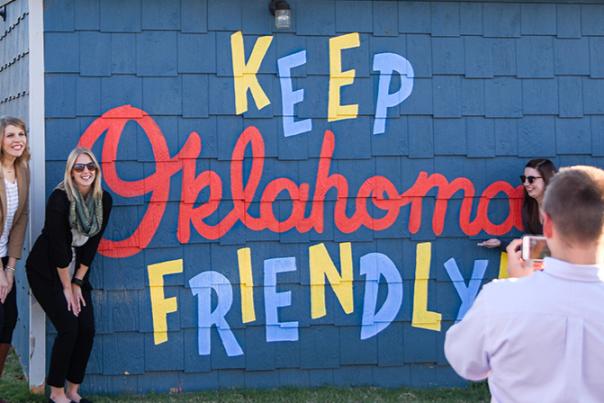 Group taking photo in front of Bleu Garten's "Keep Oklahoma Friendly" mural