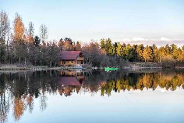 A cabin looks over a lake on a bright winter day at Log House Holidays