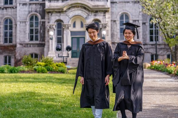 Syracuse University Commencement two grads walking on campus