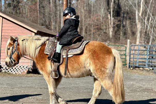 A little girl enjoys a ride at a stable in the Poconos.