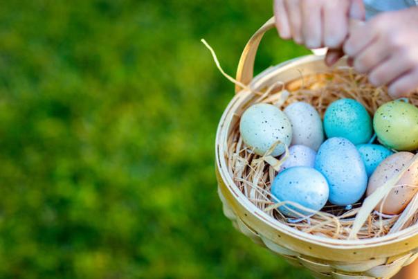 A child holds a basket of coloured eggs