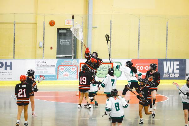 The lacrosse goalie throwing the ball away from the net.