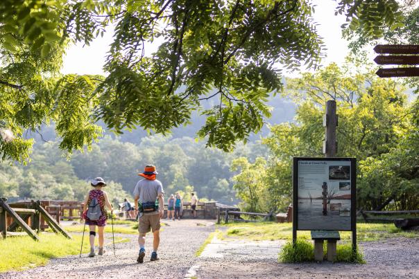 Two People Walking Next to a Great Falls Sign