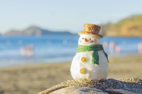 tiny snowman sitting on a warm beach