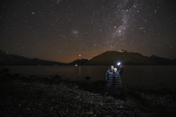 People standing on the lakefront with a starry night sky behind them