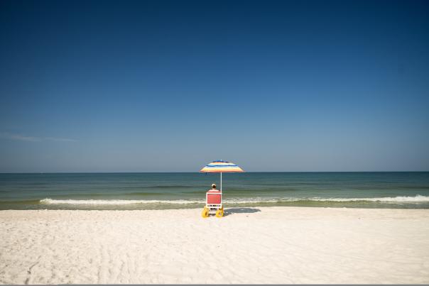 woman sitting in beach wheelchair looking out to the Gulf
