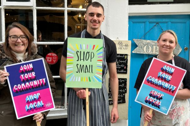 three people holding signs encouraging shoppers to shop small