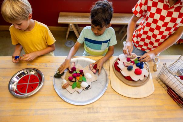 An overhead image of three kids making pizzas out of play toy food at the Madison Children's Museum.