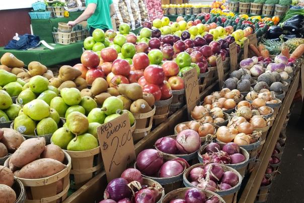 Onions, apples, pears, and other produce in baskets at the farmers market