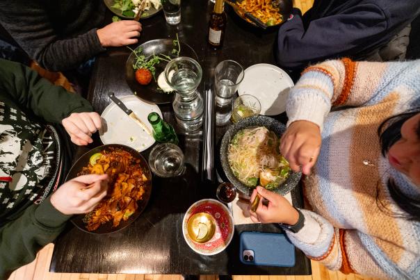 Aerial view of a dining table with various dishes, drinks, and people enjoying a meal together, creating a vibrant culinary experience.