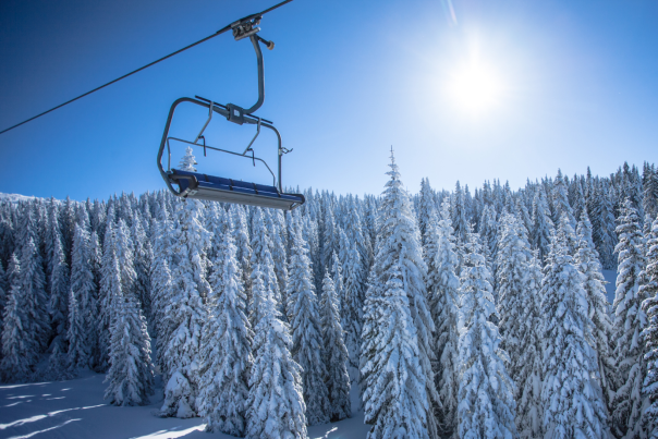 Chairlift on Sunny Day with Snow Covered Trees in Background (Chairlift - Best Ski Trail Names Blog Cover)