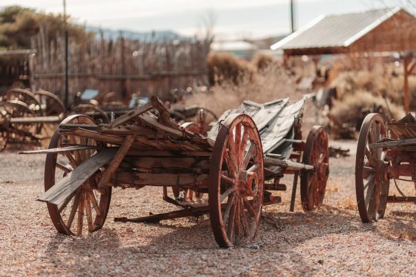 A worn western wagon with red wheels sits outside at the Frontier Homestead State Park Museum.
