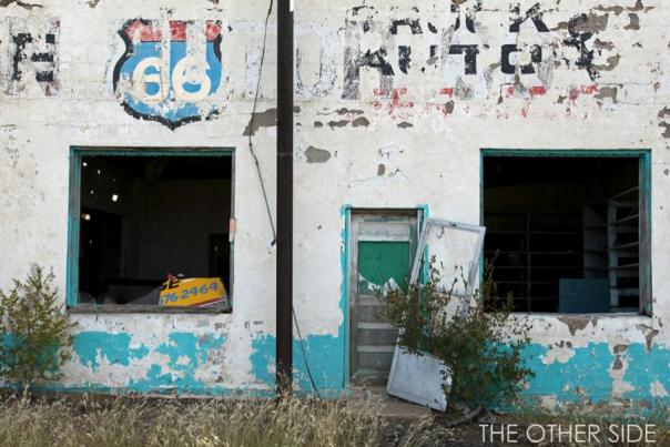 photo of an old building with a route 66 shield painted on the wall