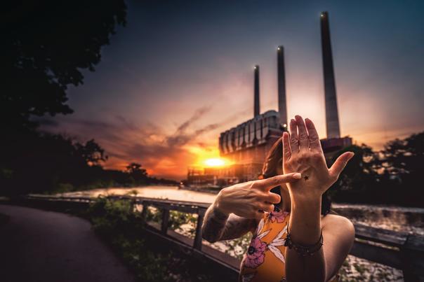 Woman pointing to a star on her hand in front of the Lansing smoke stacks