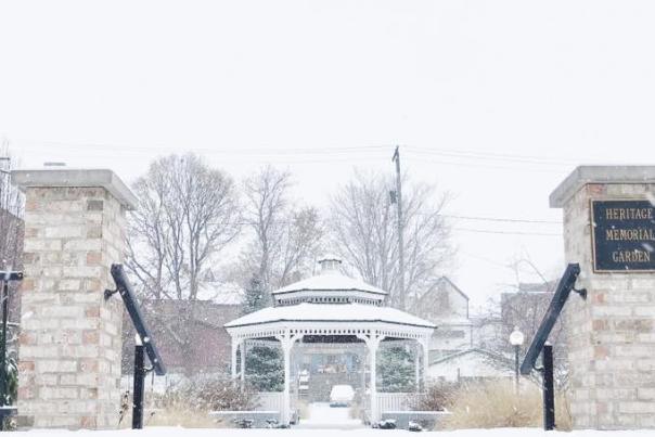 snow covered gazebo is centered between brick columns that serve as entrance to Heritage Memorial Garden