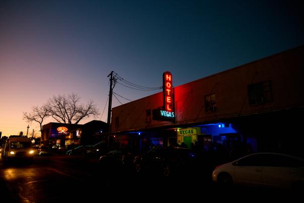 Exterior neon sign of Hotel Vegas shining on the dimly-lit East Sixth Street.