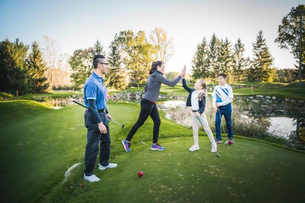 Women and kid high five on a golf course
