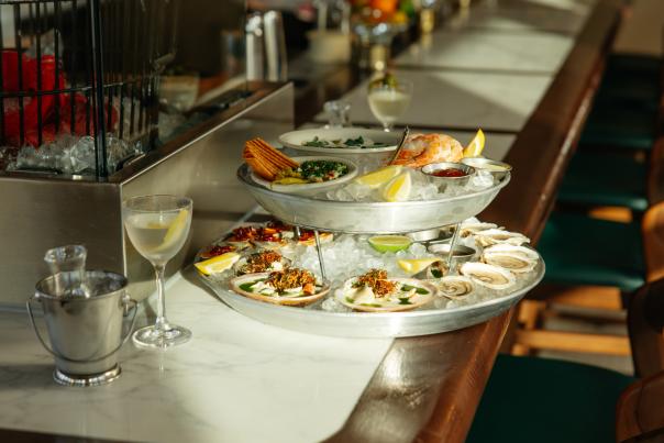 Seafood tower sitting on a marble bar top next to a martini.