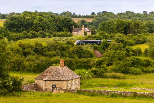 A view of North Leigh Roman Villa with a GWR train passing in the distance behind