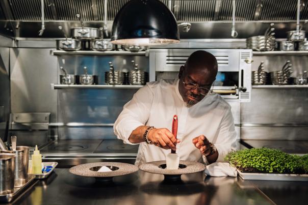 Chef Andrew Black plating food at Grey Sweater