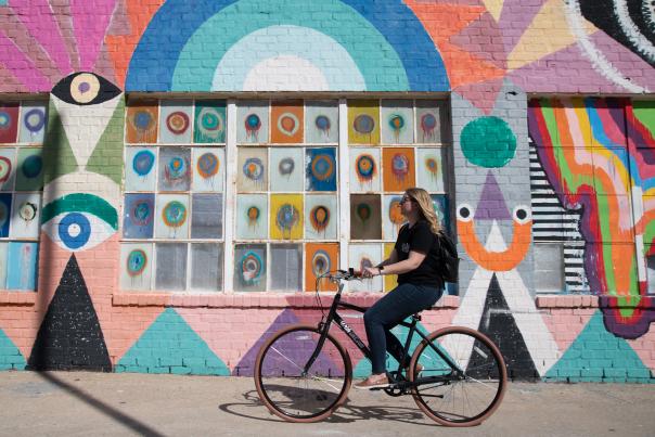 Women biking through Oklahoma City by a local mural