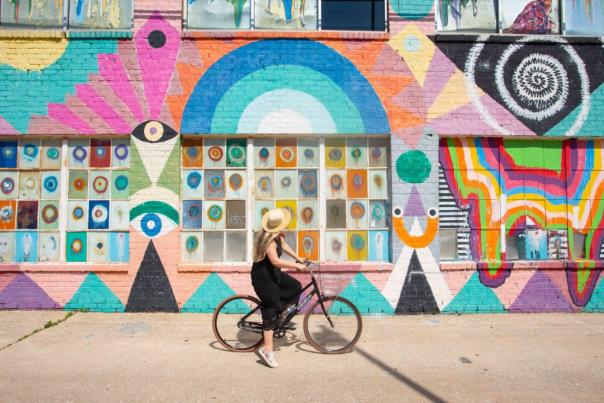 Woman looking at OKC wall mural while riding bicycle