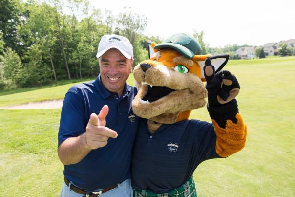 Mike Bowman and Monty the VFTCB mascot pose on a golf course