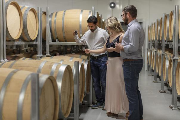 Guests sample wine during a guided barrel cellar tour at a West Kelowna winery in British Columbia’s Okanagan Valley