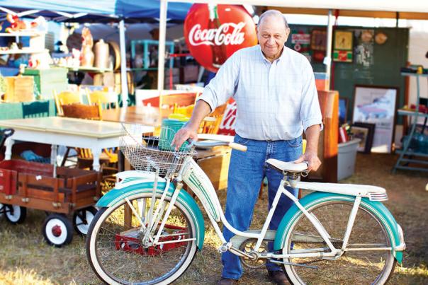 Man posing for a picture with an old bike during the Liberty Antiques Festival now in Ramseur, NC