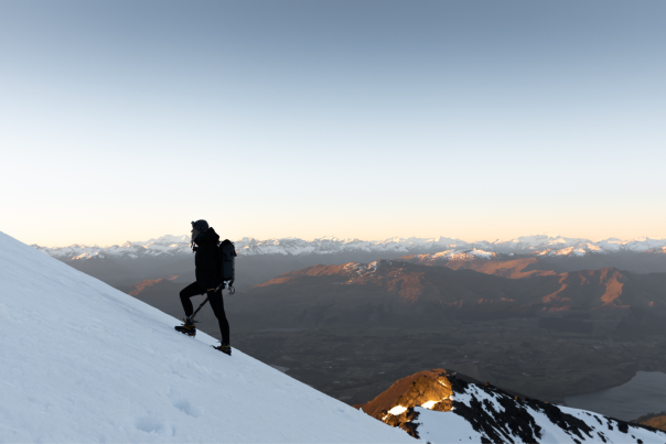 Woman hiking up the side of a snowy mountain in winter
