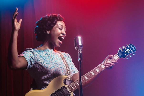Beverley Knight performing with a microphone and guitar in theatre production