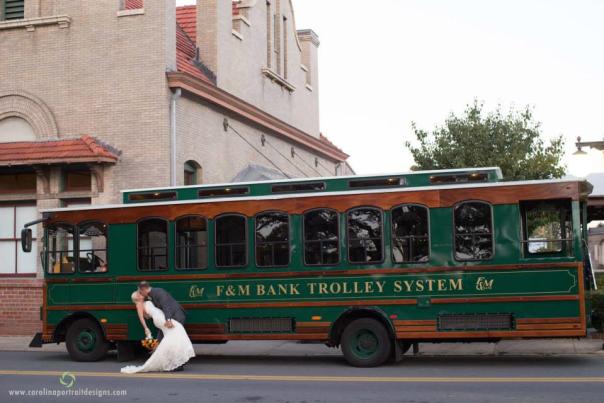 Bride and groom kissing beside a green trolley