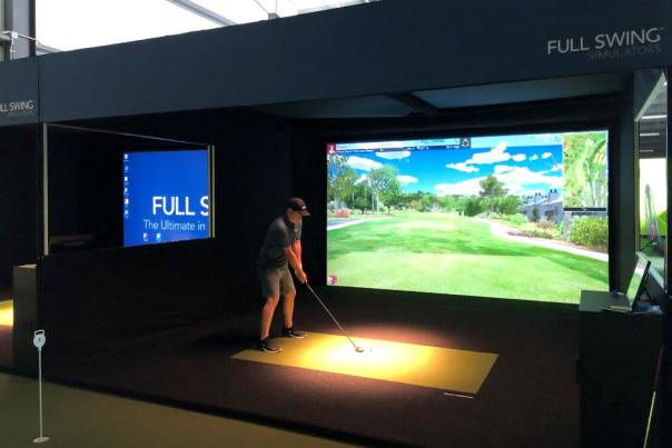 man prepares to swing his golf club at an indoor golf simulator