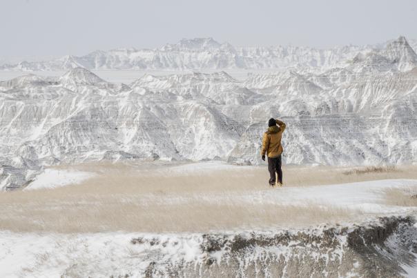 person exploring the beauty of badlands national park dusted in snow in the winter