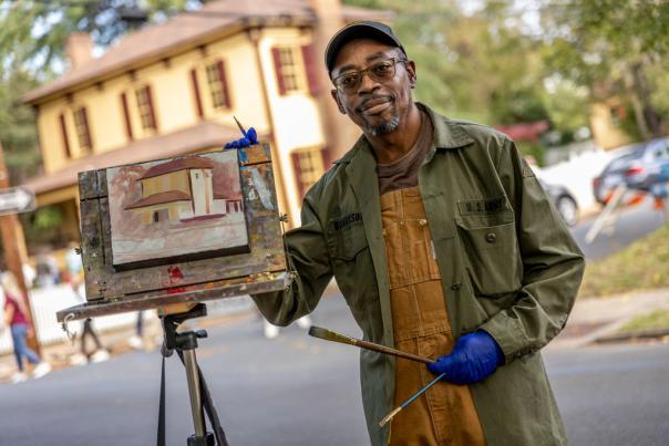 Man outside painting houses on canvas