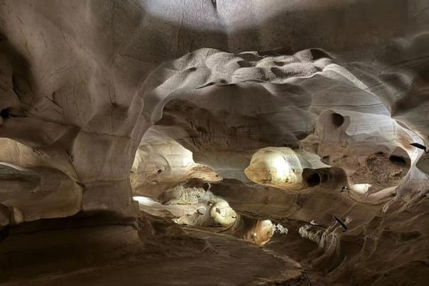 A winding walking path through Longhorn Cavern with sleek, beige rock walls on either side and large arched ceilings.