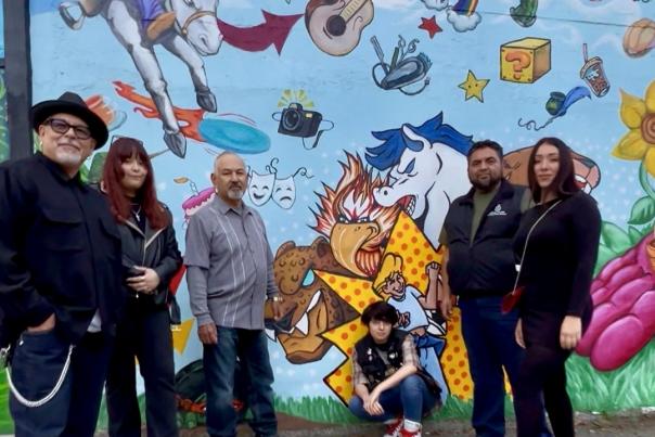 Artists posing in front of colorful mural in downtown Gilroy