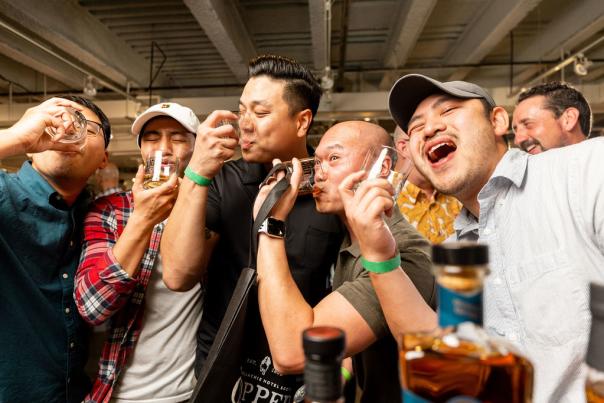 A line of patrons enjoying a glass of whiskey at the Whiskey Riot Festival