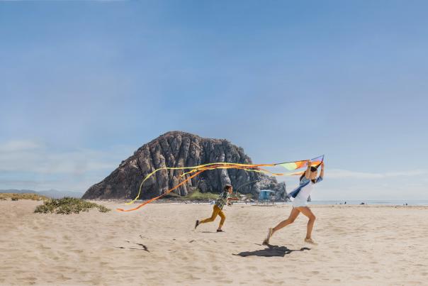 kids playing with kites on beach in front of Morro Rock