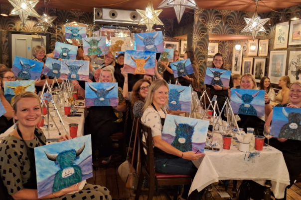 People holding their artwork at The Paint Club workshops.