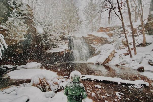 Woman standing in front of frozen waterfall.