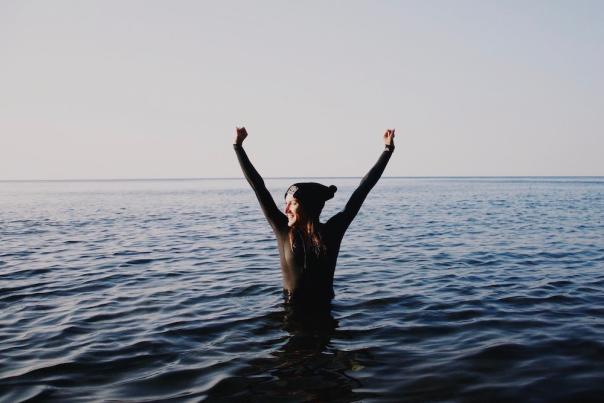 Woman in Lake Superior with arms in the air