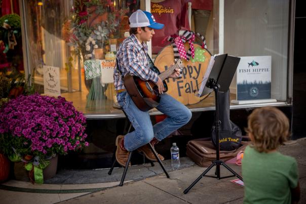 Boy playing guitar outside a downtown business