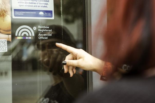 Someone pointing to the Rainbow Registered logo on a window.