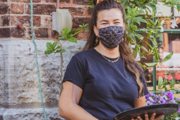 Waiter, wearing a mask, holding a tray on a restaurant patio