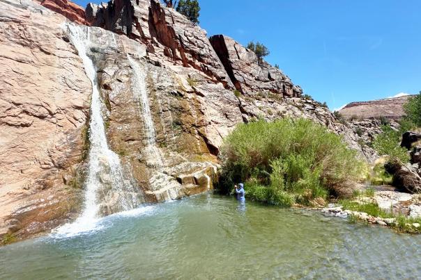 Man standing in water from Big Dominguez Canyon Waterfall
