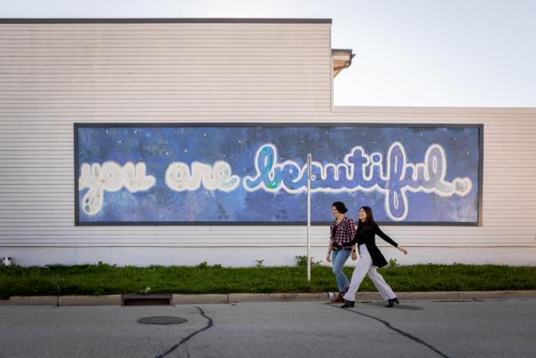 A side of a building with a mural that says "You are Beautiful" on the side in starry, colorful letters