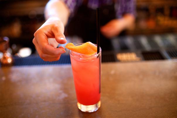 Bartender sets a citrus peel atop a mocktail.