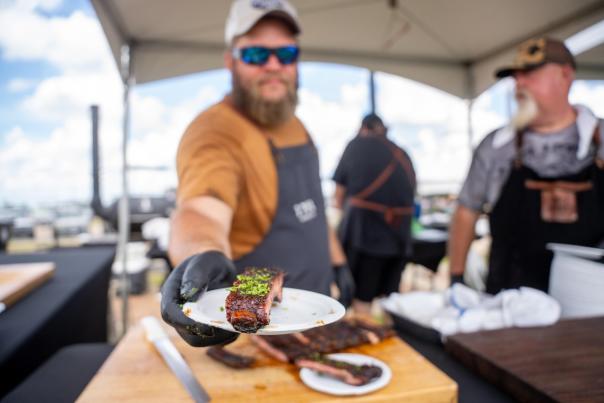man serves barbequed rib to patron at lousiana food and wine festival