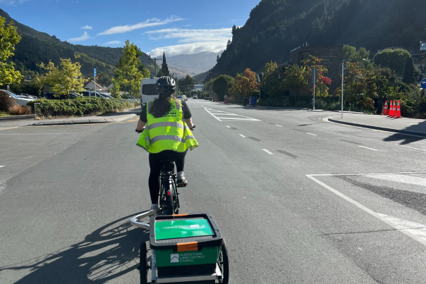 Women on bike with trailer rides along road to collect unused food from local cafes